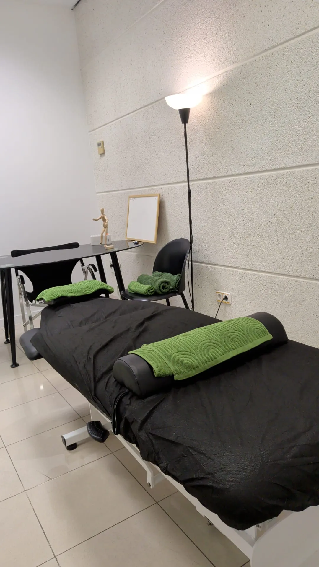 Sala de fisioterapia con camilla y toallas verdes
